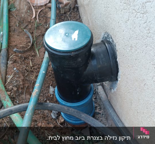 צינור פלסטיק שחור מחובר לקיר עם צינורות ירוקים